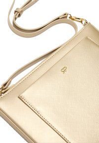 Złota torebka na ramię z fakturą, z regulowanym paskiem i małym złotym logo na przedniej kieszeni.