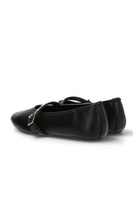Zapatos negros planos con punta afilada, material sintético suave y una delgada cinta decorativa con una pequeña hebilla a cada lado.