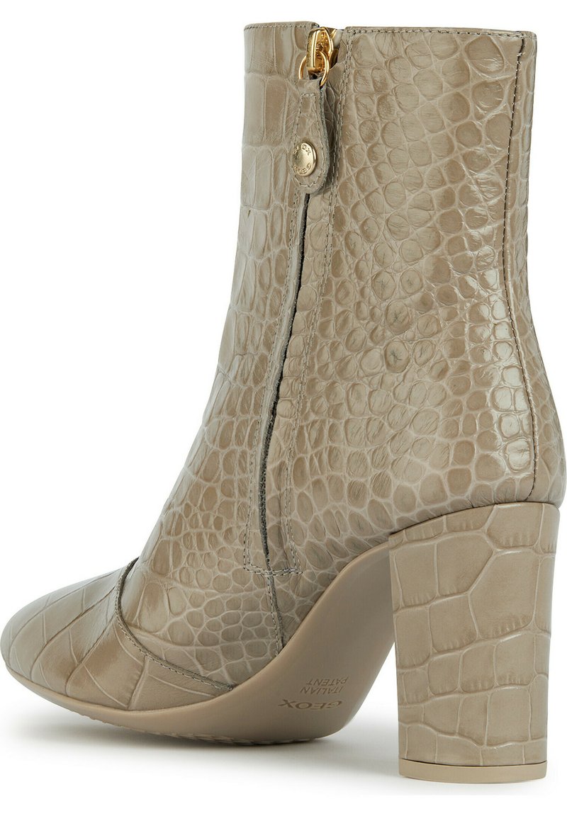 Beige Knöchelstiefel mit Krokodilstruktur, seitlichem Reißverschluss und breitem Absatz. Die glatte Oberfläche und die spitze Zehenform verleihen ihm ein modernes Design.