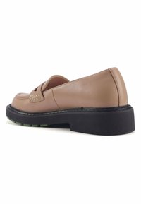 Scarpa slip-on in pelle di un beige chiaro con una tomaia texturizzata, suola piatta nera e dettagli verde sulla suola. Finitura liscia con cuciture minime.