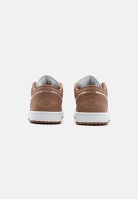 Brune lærersneakers med hvite såler. Har myk polstring, teksturdetaljering på hælen og en subtil preget logo.