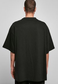 Zwart oversized t-shirt gemaakt van zachte katoen. Heeft een eenvoudige ronde hals, korte mouwen en een rechte zoom zonder zichtbare patronen.