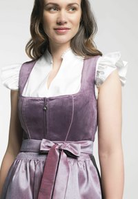 Robe en velours violet avec un corsage ajusté, des manches blanches à volants, une fermeture éclair et un nœud en satin à la taille, présentant un tissu texturé.