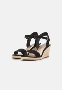 Sandali wedge neri in suede con cinturini alla caviglia e chiusure a fibbia, dotati di suole in corda intrecciata e punta aperta su uno sfondo bianco.