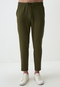 Olijfgroene joggers gemaakt van zachte stof, met een elastische tailleband met trekkoord, tapse pasvorm en zijzakken.