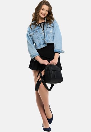Black leather backpack with adjustable straps, textured finish; worn with a cropped denim jacket, striped top, and black skirt.