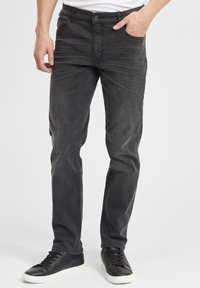 Mustad denim teksad kitsas lõikega, millel on nööbiga sulgemine, eestaskud ja peened hõõrdeefektid. Kombineeritud mustade jooksujalatsitega.
