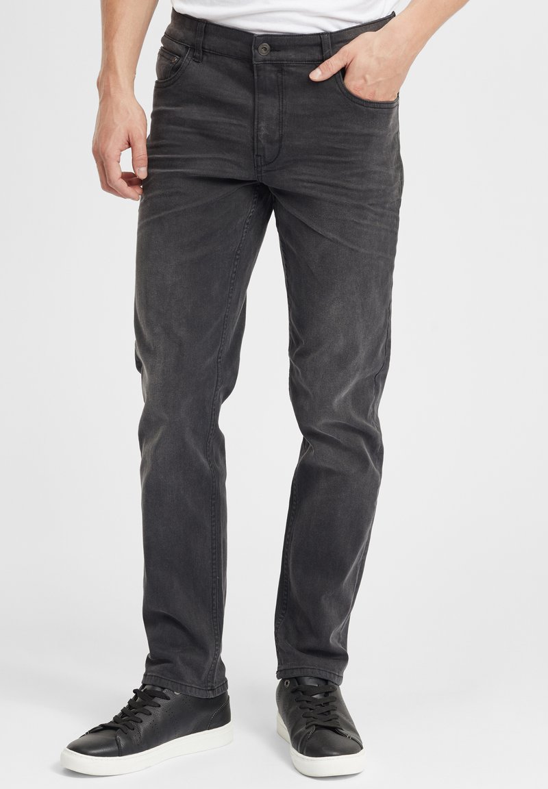 Mustad denim teksad kitsas lõikega, millel on nööbiga sulgemine, eestaskud ja peened hõõrdeefektid. Kombineeritud mustade jooksujalatsitega.