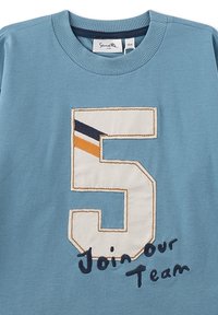 Hellblaues T-Shirt aus Baumwolle mit einer großen weißen "5" mit orangefarbenen und marineblauen Streifen. Darunter der Satz "Join our Team" in Dunkelblau.