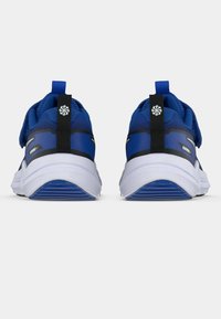 Kék sportcipők hálós felsőrész, párnázott fehér középtalppal és fekete részletekkel. A hátsó részen húzófül és texturált minta található.