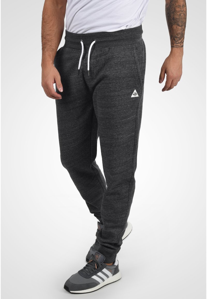 Pantalones de chándal gris oscuro hechos de un tejido suave y texturizado. Cuentan con una cintura elástica con cordones y bolsillos laterales. Pequeño logotipo en la cadera.