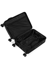 Maleta rígida negra, abierta con un interior texturizado. Con múltiples ruedas, correas elásticas para asegurar los objetos y un bolsillo con cremallera.