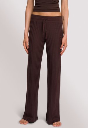 Braune gerippte Strickhose mit ausgestelltem Bein, mit einem Kordelzug am Bund und einem seitlichen Logo-Detail. Weiche Textur und lässige Passform.
