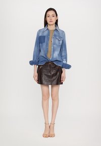 Denim shirt, light blue with dark accents, button-up front and chest pocket. Brown leather mini skirt with front zipper detail. Tan heeled sandals.