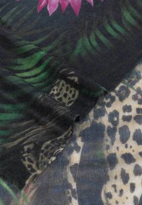 Satin scarf featuring dark green tropical leaf print, pink flowers, and beige leopard spots, with a soft, smooth texture and frayed edges.