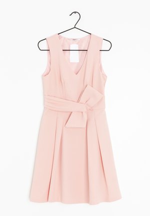 Vestito rosa chiaro senza maniche con scollo a V e cintura larga legata a fiocco, appeso a una gruccia nera su sfondo bianco.