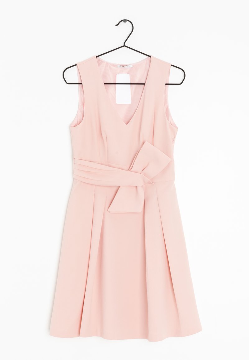 Robe rose clair sans manches avec col en V et large ceinture nouée en nœud, accrochée à un cintre noir sur fond blanc.