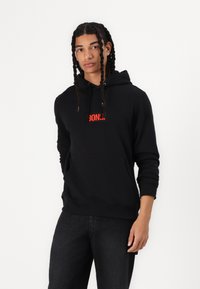 Black hoodie with a front kangaroo pocket, featuring a red "BONG." logo. Made of soft fabric, it has a drawstring hood and ribbed cuffs.