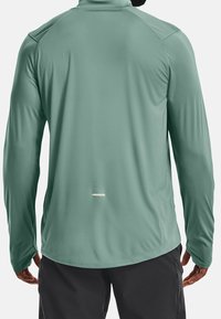 Maglia leggera a maniche lunghe di colore verde spento, con colletto alto, tessuto morbido e un piccolo accento riflettente vicino all'orlo.