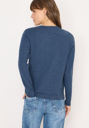 Dunkelblauer gestrickter Pullover mit langen Ärmeln, Rundhalsausschnitt und gerippten Bündchen. Getragen mit hellen Jeans und zeigt einen lässigen Schnitt.