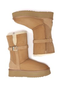 Tan suede ankle boots with soft fur lining, featuring a buckle accent, flat rubber sole, and a stitched design along the seams.
