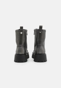 Bottines en cuir noir avec une semelle épaisse, fermeture éclair sur le côté et une languette à l'arrière. Texture lisse avec des détails de couture minimaux.