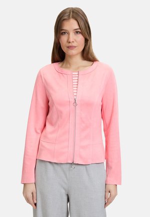 Rosa Kunstwildlederjacke mit rundem Ausschnitt, Reißverschluss und genähten Details. Kombiniert mit einem gestreiften Unterhemd und hellgrauen Hosen.