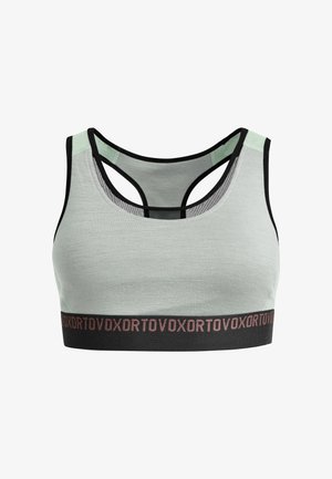 Light green sports bra with black accents and a mesh back. Features a black elastic band with pink text, and a fitted design.
