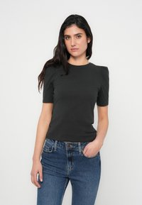 Donkergrijze T-shirt met korte mouwen en een ronde hals, voorzien van subtiele pofmouwen en een aansluitend model, gecombineerd met blauwe denim jeans.