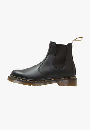 Stivale Chelsea in pelle nera con pannelli laterali elasticizzati, punta rotonda e suola trasparente in gomma con cuciture arancioni a contrasto.