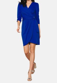 Královsky modré zavinovací šaty se třičtvrtinovými rukávy, opásaným pasem a drapeným předním dílem. Vyznačují se hladkým materiálem a délkou po kolena.