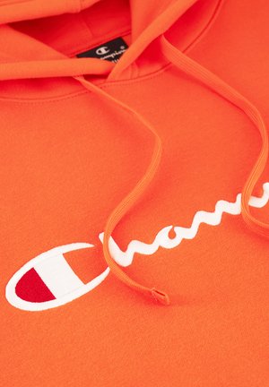 Sudadera naranja hecha de tela suave. Presenta un logo bordado en blanco y cordones. Textura plana con color uniforme y detalles mínimos.