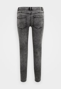 Jeans de denim cinza achatados com um acabamento desbotado, apresentando dois bolsos traseiros e uma cintura de altura média. O tecido possui um aspeto liso e texturizado.