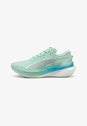 Scarpa da ginnastica verde chiaro con tomaia in rete, dettagli in argento e suola blu sfumata. Presenta una soletta imbottita per ulteriore supporto.