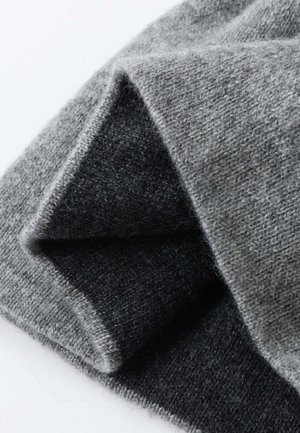 Grau und dunkelgrauer Strickstoff mit weicher Textur und sichtbaren Fasern, gefaltet, um das geschichtete Design und den Farbkontrast zu zeigen.