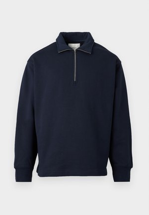 Sudadera de cuello alto de color azul marino, con cierre de media cremallera, fabricada en una suave tela, con mangas largas y un corte relajado.