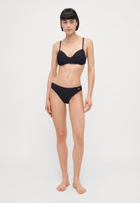 Črni dvo delni bikini z zasukanjem na modrčku, nastavljivimi naramnicami in enostavnim trikotnim krojem na dnu. Diskreten poudarek blagovne znamke.