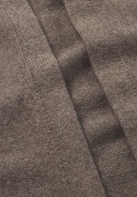 Tessuto a maglia marrone con una superficie testurizzata caratterizzata da linee distinte e sfumature variabili, che enfatizza la qualità morbida e calda del materiale.