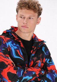 Bever jacket met een multikleurig abstract patroon in zwart, rood en blauw. Gemaakt van lichtgewicht stof, met een rits en trekkoorden.