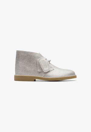 Stivaletti alla caviglia in suede grigio chiaro con lacci, suola in gomma e toppa decorativa con bordi perforati. Logo del marchio sul lato.