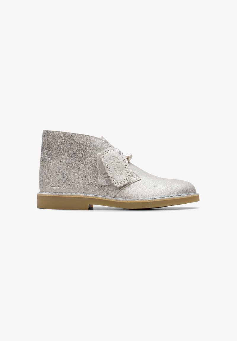 Stivaletti alla caviglia in suede grigio chiaro con lacci, suola in gomma e toppa decorativa con bordi perforati. Logo del marchio sul lato.