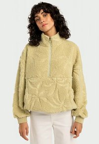Pullover de fleece em verde claro, com colarinho alto, fecho parcial em zíper e padrão texturizado de folhas. Punhos canelados e um ajuste descontraído.