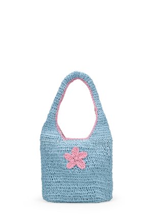Bolso de ganchillo azul con una decoración de flor rosa y ribete rosa alrededor del asa y la abertura, de pie sobre un fondo blanco.