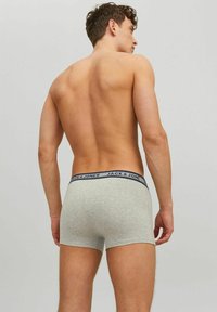 Shirtless man seen from the back wearing light gray boxer briefs with a navy waistband labeled "JACK & JONES."