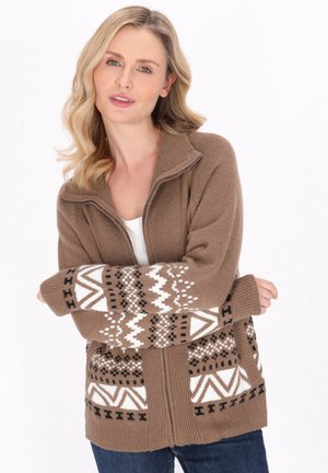 Bruine zip-up trui met geprinte mouwen met witte en zwarte geometrische patronen. Ribbelstructuur en twee voorzakken.