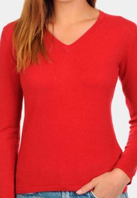 Haut rouge à manches longues et col en V en tissu côtelé, avec une silhouette ajustée et une texture lisse. Idéal pour le superposition.