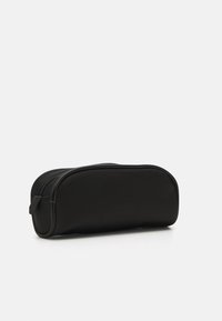 Svart pennfodral med avrundad form, tillverkat av slätt tyg, med dubbel dragkedjestängning och minimalistisk design.