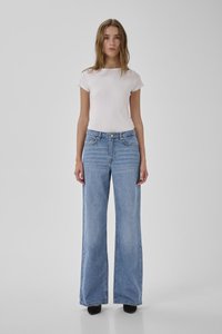 Baltas ribuotas trumpomis rankovėmis viršus kartu su aukštu liemeniu plačių kojų šviesiai mėlynų džinsų. Lygus paviršius su kišenėmis ir prigludusia siluetu.