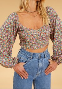 Blommig croppad topp med rynkad tyg, med fyrkantig halsringning och puffärmar, kombinerad med högmidjade blå jeans i denim.