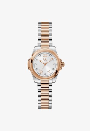 Reloj de pulsera metálico en oro rosa y plata con caja redonda, esfera blanca, números romanos y marcadores de hora con diamantes en una pulsera de eslabones.